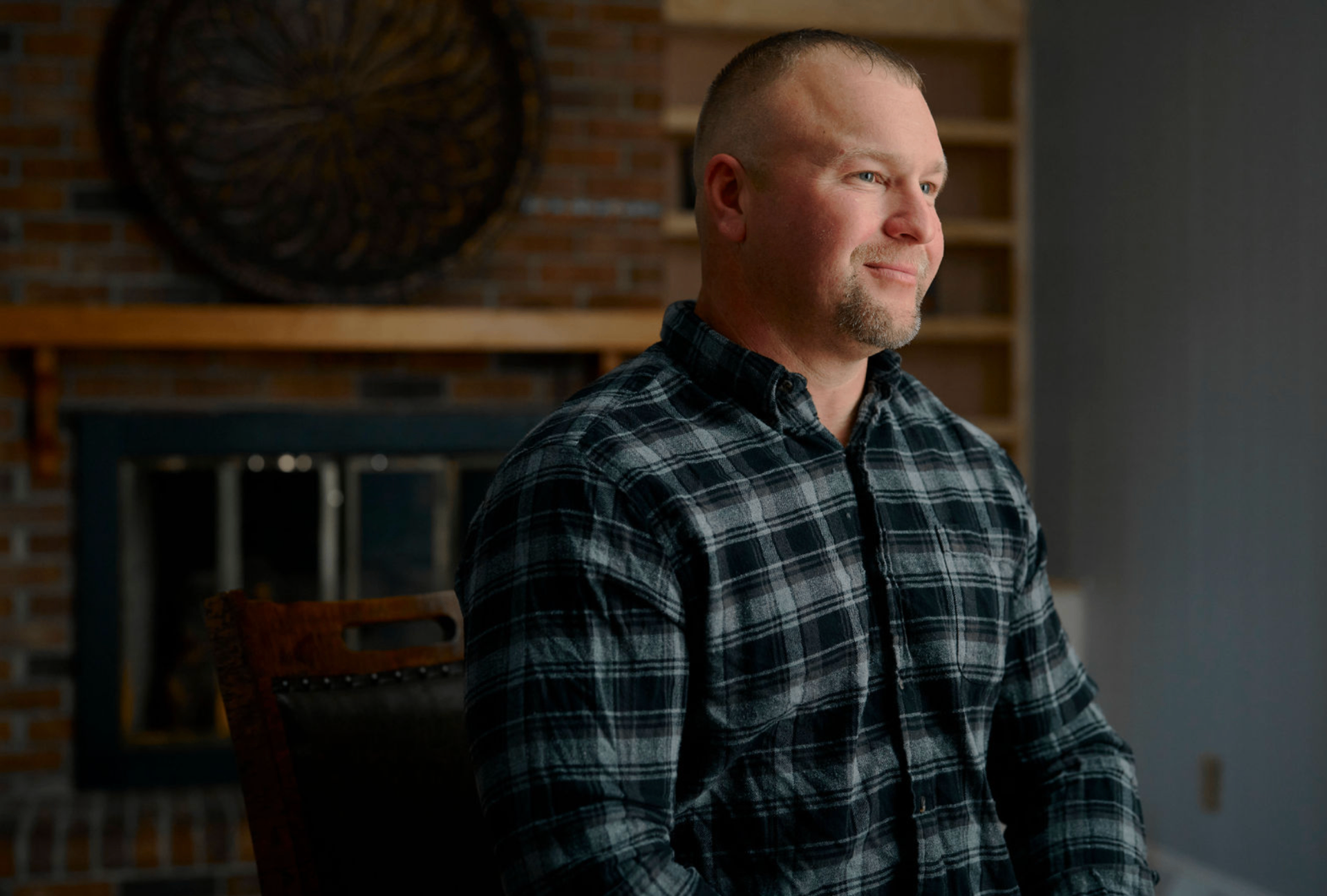 SECU member portrait — man by fireplace in flannel