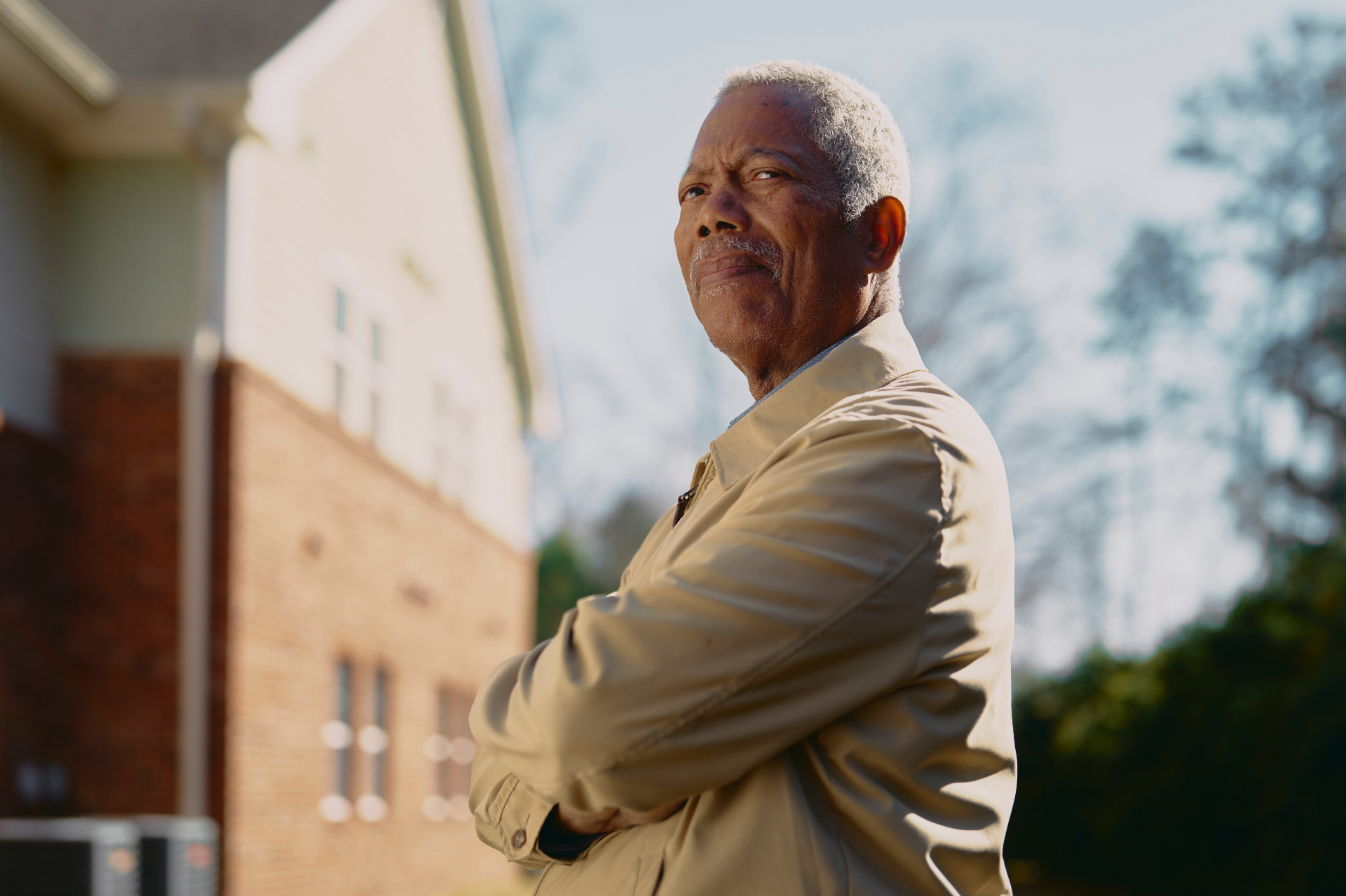 SECU member portrait — elder with arms crossed outside home